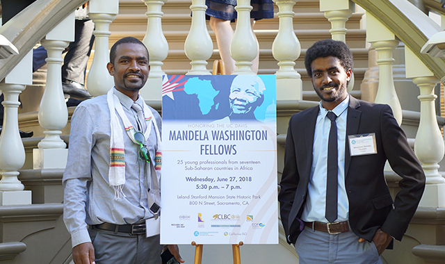 two men standing on either side of a sign that reads Mandela Washington Fellowship
