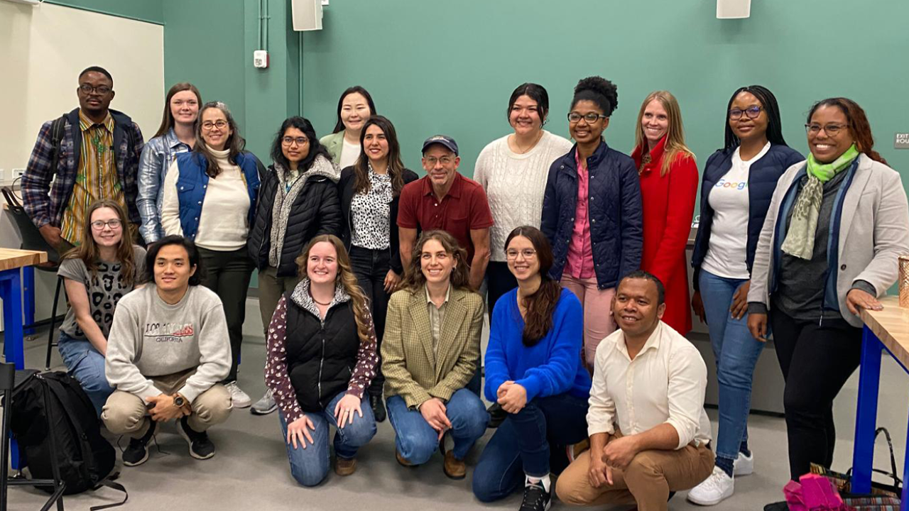 Members of the D-Lab Humphrey Fellowship seminar pose for a group picture in a classroom with green walls.